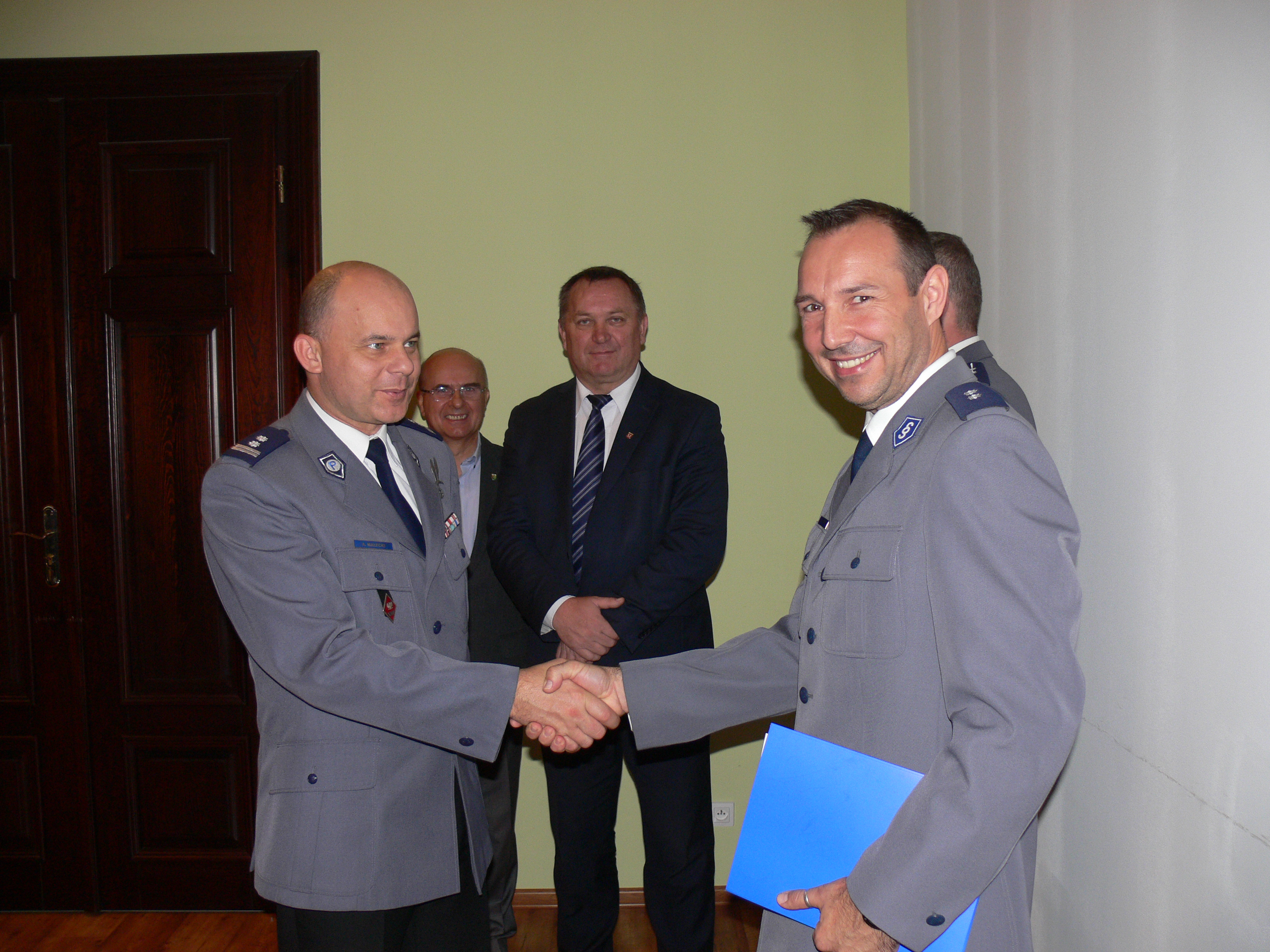 zastępca komendanta miejskiego policji we Wrocławiu wręcza nominację nowemu komendantowi Komisariatu Policji w Kątach Wrocławskich, w tle stoi burmistrz Antoni Kopeć i sekretarz gminy Mietków Ireneusz Słoma