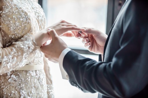 zdjęcie przedstawia dłonie mężczyzny i kobiety w czasie nakładania obrączek ślubnych