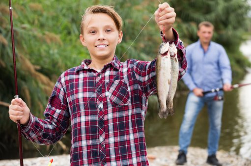 zdjęcie przedstawia chłopca prezentującego dwie złowione ryby