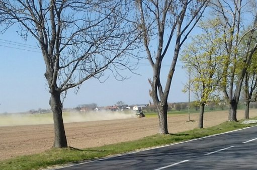 po polu jedzie traktor , za nim chmura pyłu